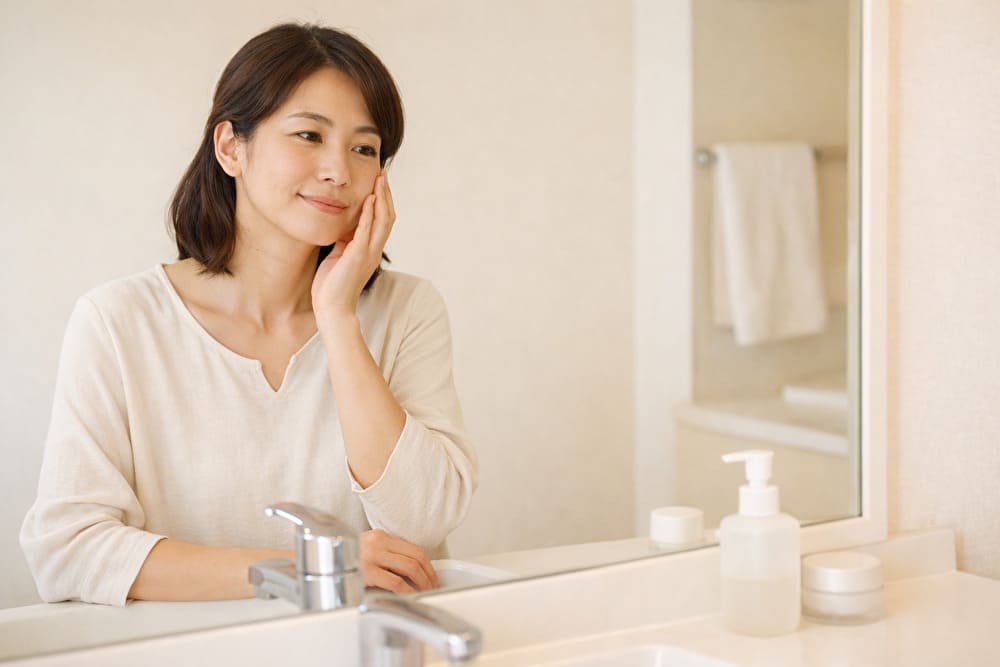 40代女性が洗面台で自分の肌状態を落ち着いて確認している様子