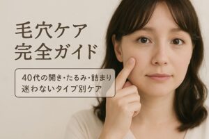 40代前半のかわいらしい日本人女性が、鏡を見るように頬の毛穴を気にして指で触れている横長の写真。やわらかな光とベージュ系の背景で、清潔感と優しさを感じる雰囲気。「毛穴ケア完全ガイド」というタイトルと「40代の開き・たるみ・詰まり　迷わないタイプ別ケア」というサブタイトルが、ふんわりした書体で配置されている。