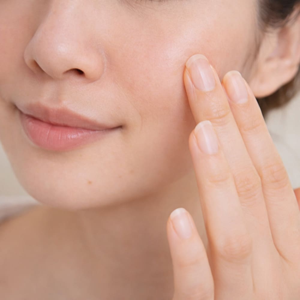 夜ケア後の肌にそっと触れる40代女性のイメージ